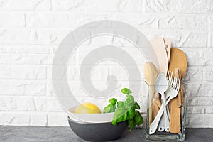 Simple minimalist kitchen shelf. Cutlery, kitchen tools, greens in a glass, fruits on a light background. Scandy style