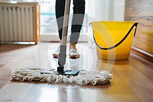 Simple mop on laminate floor with water bucket in background photo