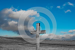 Simple oak catholic cross in black and white, blue sky with stormclouds photo
