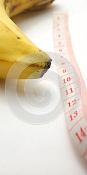 Simple Photo Conceptual Illustration for Penis Size, Banana with Pink Plastic Tailor meter on white background