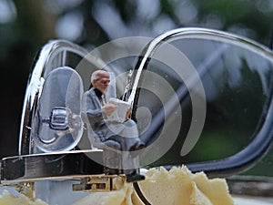 Simple Photo Conceptual Photo Mini Figure Old Man Toy Sitting and Reading News Paper, Journal or Book at black Plastic eyeglass,