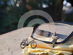 Simple Photo Conceptual Photo Mini Figure Old Man Toy Sitting and Reading News Paper, Journal or Book at black Plastic eyeglass,