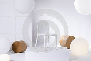 A simple, plastic, white chair standing on a podium against white background. Real photo of furniture presentation in a shop