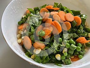 Simple salad with lots of carrots French beans and spinach tossed with corn