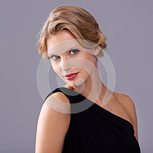 Simple yet sophisticated beauty. A gorgeous young woman in an evening gown while isolated on a grey background.