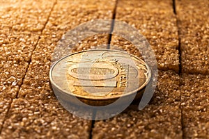 A simple yet striking image of a golden coin and a pile of brown sugar, representing the balance between the material