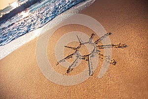 Simple sun drawing in the sand on the beach, sunrise shot