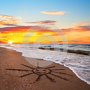 Simple sun drawing in the sand on sunset beach