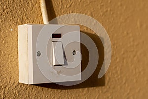 A simple white electrical light switch on a brown wall outdoors in sunshine. Industrial, residential or DIY construction concepts