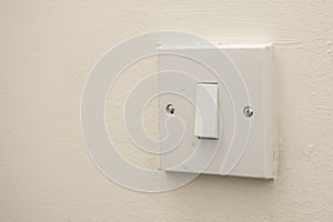 A simple white electrical light switch on a white wall. Industrial, residential or DIY construction concepts
