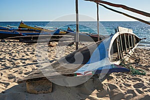 Simple wooden fishing boats on a sandy beach near small Madagascar village, calm sea in background