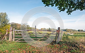 Simple wooden gate closed with knotted orange-colored rope and a