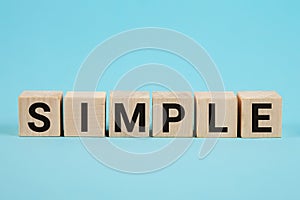 SIMPLE word from wooden blocks with letters, to make something easy, keep it simple concept, blue background