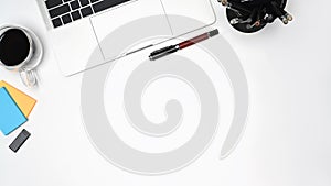 Simple workplace with laptop computer, sticky notes and coffee cup on white table.