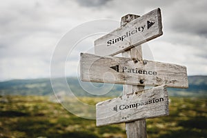 simplicity patience compassion text engraved on old wooden signpost outdoors in nature