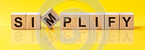 simplify word is made of wooden building blocks lying on the yellow table, concept