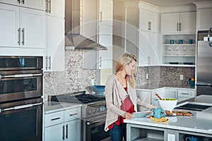 Simplifying the baking experience with smart technology. a young woman using a digital tablet while baking at home.