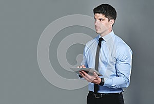 Simplifying the hard work with smart tools. Studio shot of a young businessman using a digital tablet against a grey