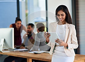 Simplifying her tasks with just one device. a young businesswoman working on a digital tablet with her colleagues in the