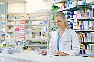 Simplifying pharmaceutical tasks with smart technology. a young pharmacist using a digital tablet at the checkout