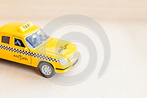 Simply design yellow vintage retro toy car Taxi Cab model on wooden background. Automobile and transportation symbol. City traffic