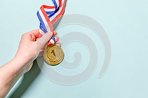 Simply flat lay design hand holding winner or champion gold trophy medal  on blue colorful background. Victory