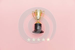 Simply flat lay design winner or champion gold trophy cup and 5 stars rating  on pink pastel background. Victory first