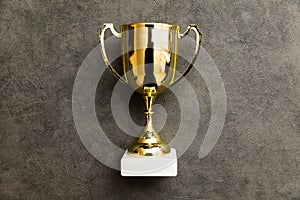 Simply flat lay design winner or champion gold trophy cup on concrete stone grey background. Victory first place of