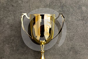 Simply flat lay design winner or champion gold trophy cup on concrete stone grey background. Victory first place of