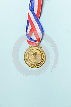 Simply flat lay design winner or champion gold trophy medal isolated on blue colorful background. Victory first place of