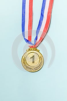 Simply flat lay design winner or champion gold trophy medal isolated on blue colorful background. Victory first place of