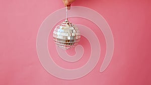 Simply minimal design female woman hand holding Christmas ornament disco ball isolated on pink pastel colorful trendy