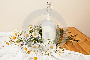 Simply stylish wooden kitchen with bottle of milk and glass on table, summer flowers camomile, healthy foog moring