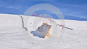 Sinaia ski domain. View of a medium difficulty slope in Valea Dorului, a wooden protection fence, and an old, red, chairlift.