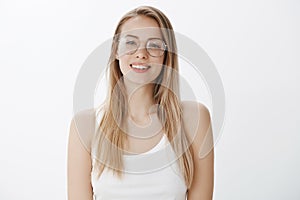 Sincere and friendly-looking young european woman in prescribed glasses with blond hair smiling and looking kind at