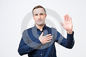 Sincere happy man raising palm and holding hand on chest, promising to me honest