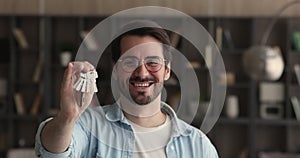 Sincere happy young male homeowner showing keys to camera.