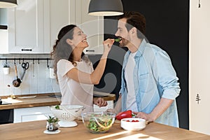 Sincere laughing hispanic woman feeding happy man.