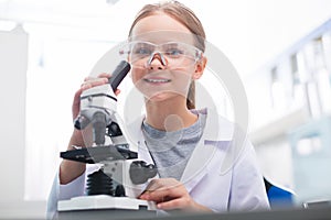 Sincere merry girl learning work with microscope