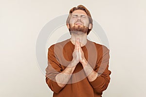 Sincere request to god. Portrait of imploring man with beard in sweatshirt praying up heartily, feeling guilty
