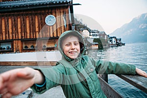 Sincerely smiling boy near the bot pier on mountain lake
