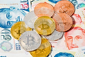 Singapore Dollar banknotes and Bitcoin Cryptocurrency coins on W