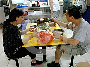 Two people eat at a typical Singapore food court or Hawker