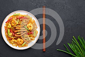 Singapore Mei Fun in white plate on dark slate background. Singapore Noodles is chinese cuisine dish. Chinese food
