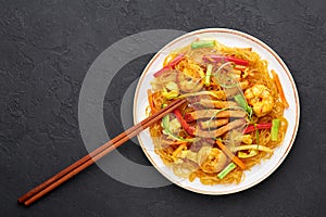 Singapore Mei Fun in white plate on dark slate background. Singapore Noodles is chinese cuisine dish. Chinese food