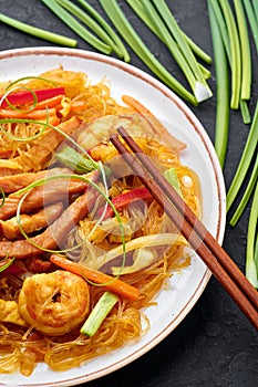 Singapore Mei Fun in white plate on dark slate background. Singapore Noodles is chinese cuisine dish. Chinese food