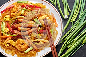 Singapore Mei Fun in white plate on dark slate background. Singapore Noodles is chinese cuisine dish. Chinese food