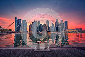 Singapore Skyline and view of business district downtown with wooden walkway on Marina Bay at sunset.