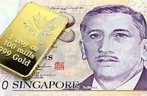 A Singapore two dollar bill with a gold bar in macro