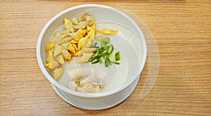 Singaporean fish porridge served with crackers and onion leaves